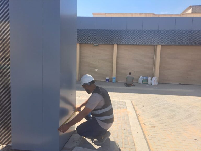 فني يركب كسوة واجهة لعمود مبنى تجاري